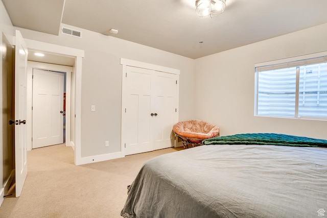 bedroom featuring light carpet, visible vents, baseboards, and a closet