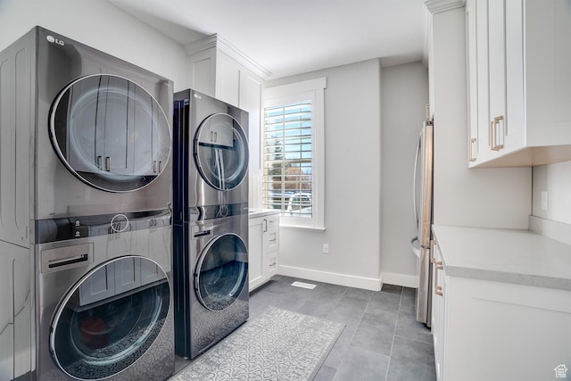 laundry room with stacked washer and dryer, baseboards, and cabinet space