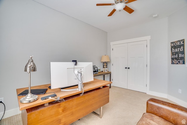 office area with baseboards, a ceiling fan, and light carpet