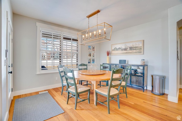 dining space featuring a chandelier, baseboards, and wood finished floors