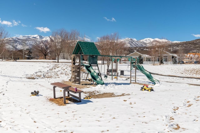snow covered playground featuring a mountain view and playground community
