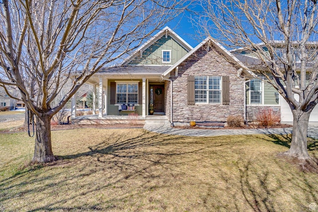 view of front of home with stone siding, a front lawn, and covered porch