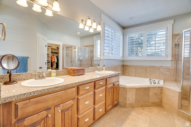 bathroom featuring a shower stall, a garden tub, a sink, and a spacious closet