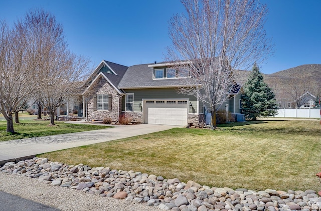 craftsman house featuring central air condition unit, stone siding, fence, a front lawn, and concrete driveway