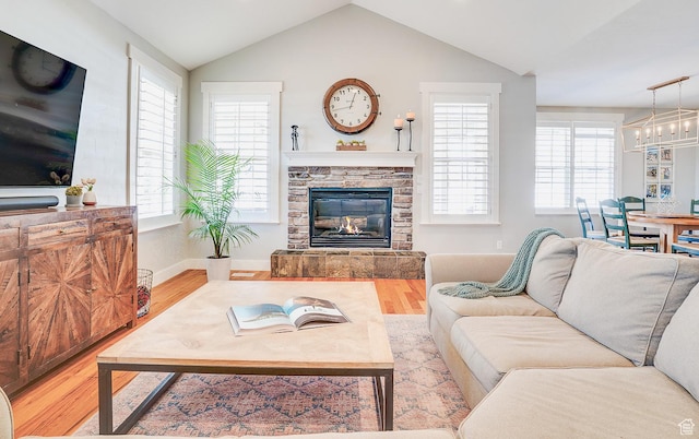 living area with a wealth of natural light, a fireplace, vaulted ceiling, and wood finished floors