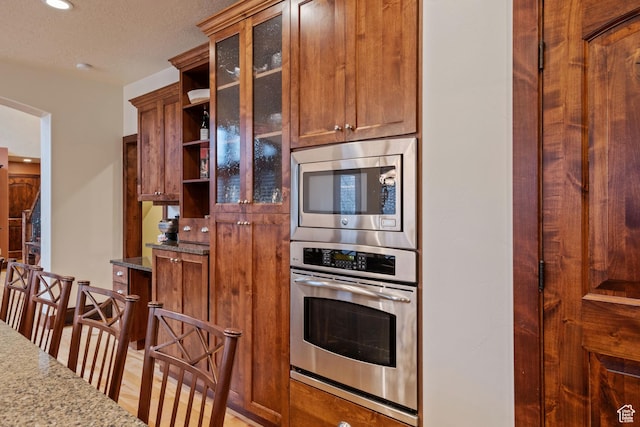 4048 W Ivy Ave, Mountain Green, UT 84050 - kitchen featuring stainless steel appliances, open shelves, light stone countertops, glass insert cabinets, and recessed lighting