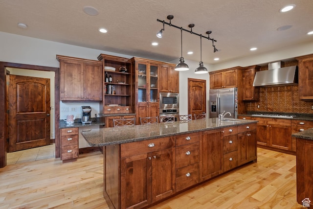 4048 W Ivy Ave, Mountain Green, UT 84050 - kitchen with wall chimney range hood, appliances with stainless steel finishes, a center island with sink, light wood-style floors, and open shelves