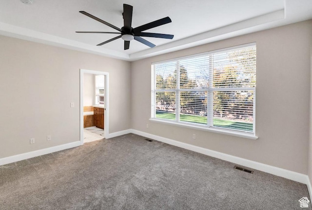 carpeted spare room featuring a ceiling fan and baseboards