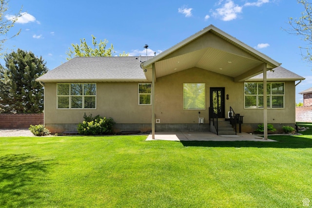 rear view of property with stucco siding, a patio area, and a yard