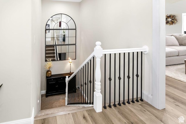 staircase featuring wood finished floors and baseboards