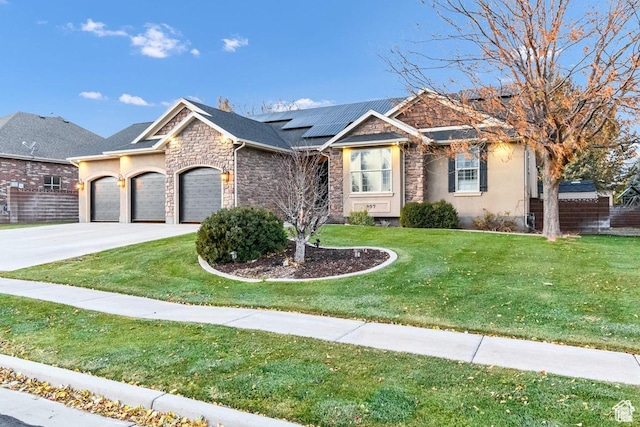 view of front of home featuring a garage, roof mounted solar panels, stone siding, a front yard, and driveway