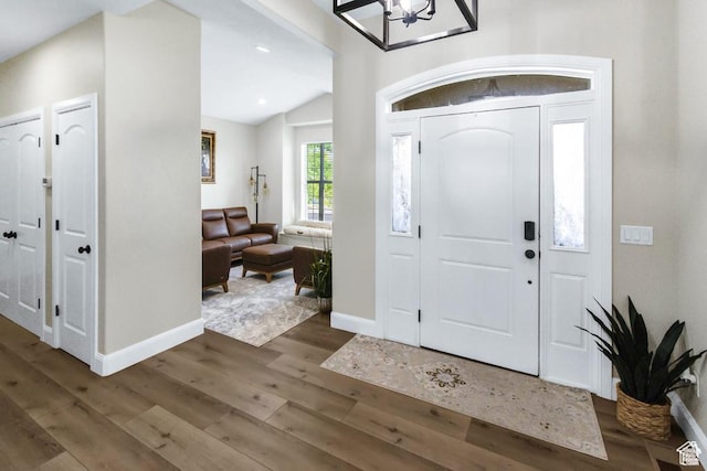foyer featuring wood finished floors, a chandelier, baseboards, vaulted ceiling, and recessed lighting