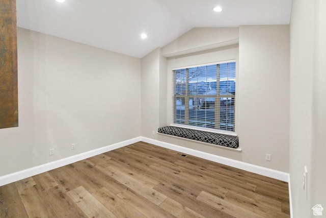 spare room with baseboards, wood finished floors, recessed lighting, and vaulted ceiling