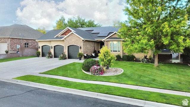 view of front of property featuring stone siding, solar panels, a front yard, and driveway