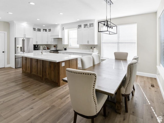 dining room with light wood finished floors, a chandelier, baseboards, and recessed lighting