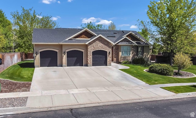 view of front of home with a garage, roof mounted solar panels, driveway, stone siding, and roof with shingles