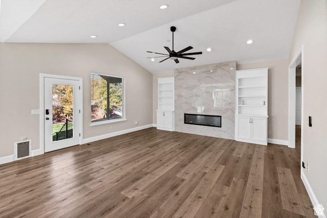 unfurnished living room with lofted ceiling, wood finished floors, built in shelves, baseboards, and a ceiling fan