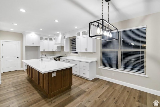 kitchen featuring high end stainless steel range oven, baseboards, light wood-style floors, glass insert cabinets, and white cabinetry