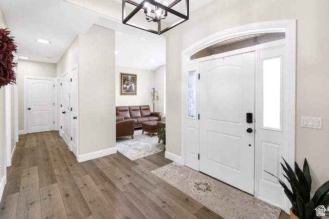 entrance foyer with light wood-style flooring, a chandelier, baseboards, and recessed lighting