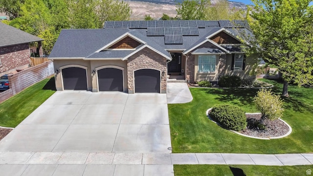 craftsman-style home featuring an attached garage, driveway, stone siding, roof mounted solar panels, and roof with shingles