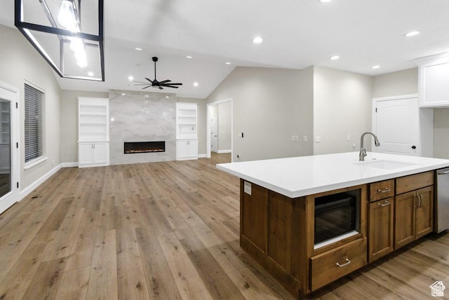 kitchen featuring a sink, black microwave, light wood-style floors, a ceiling fan, and light countertops