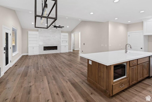 kitchen featuring a sink, lofted ceiling, light wood-type flooring, light countertops, and a premium fireplace