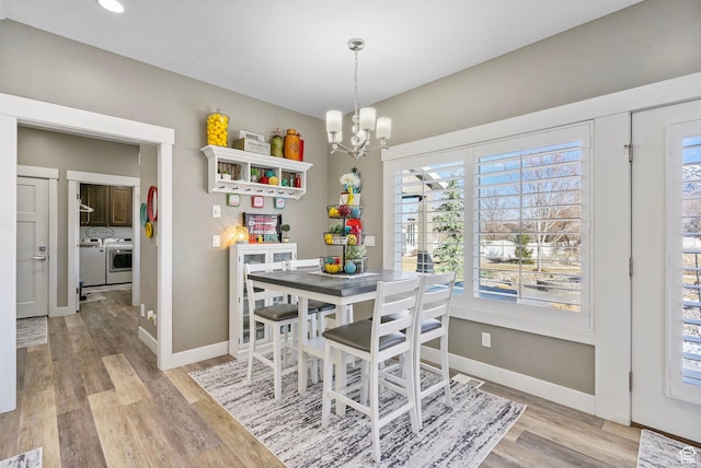 dining space featuring a chandelier, separate washer and dryer, light wood finished floors, and baseboards