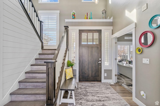 foyer entrance with stairs, baseboards, and wood finished floors