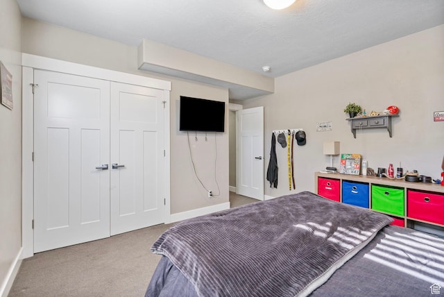 carpeted bedroom with a textured ceiling, a closet, and baseboards