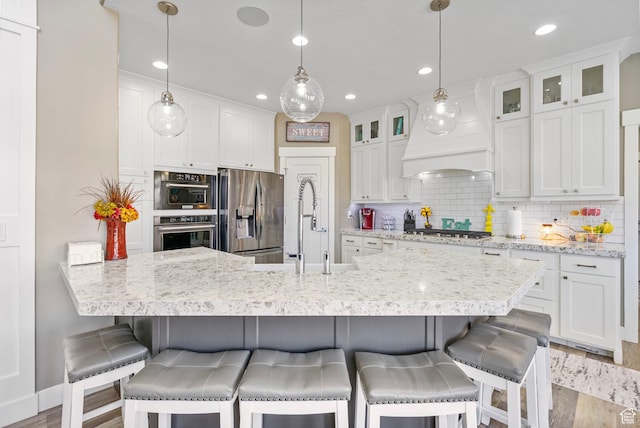 kitchen with wood finished floors, white cabinetry, decorative backsplash, and appliances with stainless steel finishes