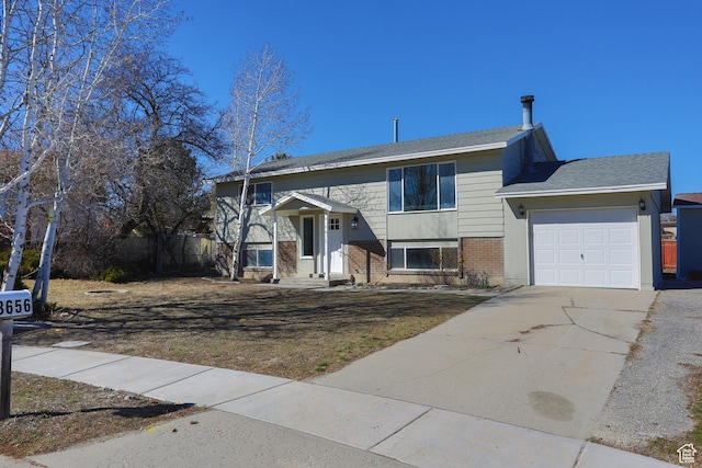 raised ranch featuring fence, brick siding, a garage, and driveway