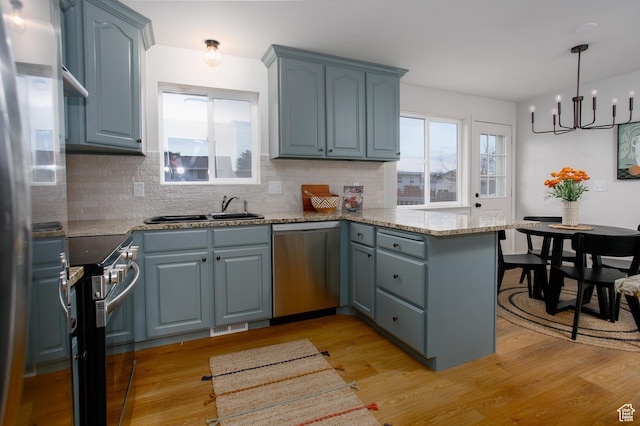 kitchen featuring plenty of natural light, a peninsula, stainless steel appliances, and light wood-type flooring