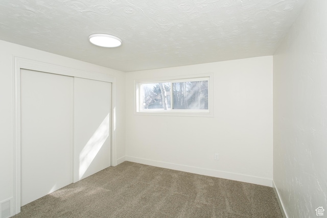 unfurnished bedroom with baseboards, carpet, a closet, and a textured ceiling