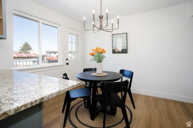 dining area featuring an inviting chandelier, light wood-style flooring, and baseboards