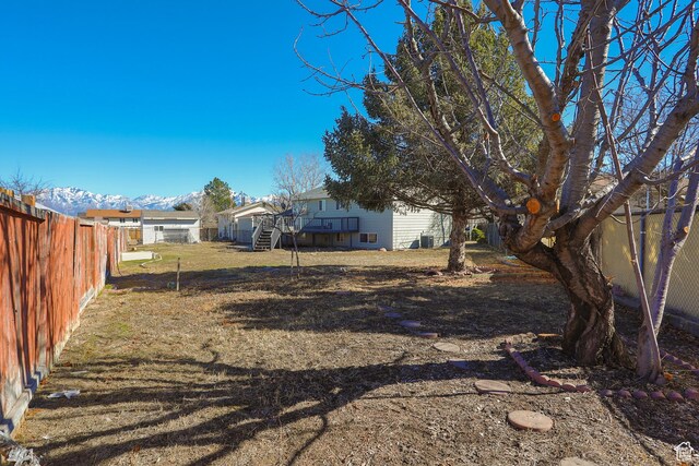 view of yard with stairway, a deck with mountain view, and a fenced backyard