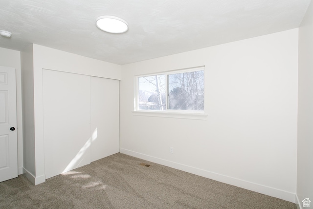 unfurnished bedroom with a closet, visible vents, baseboards, and carpet floors