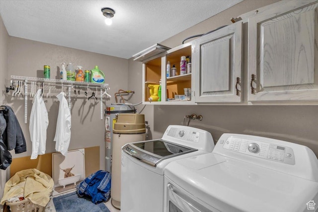 washroom with gas water heater, cabinet space, a textured ceiling, and washer and clothes dryer