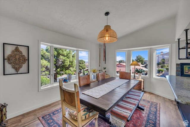 dining space with baseboards, a textured ceiling, and light wood finished floors
