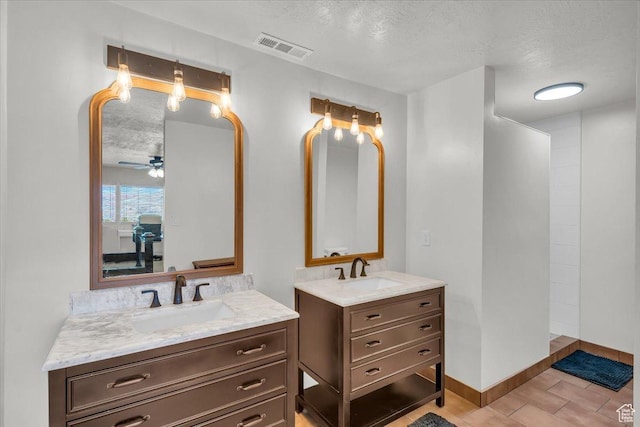 bathroom with visible vents, a textured ceiling, two vanities, and a sink