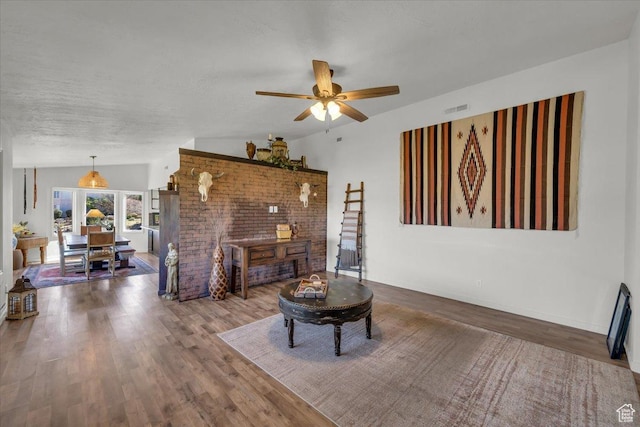 living area with a textured ceiling, lofted ceiling, wood finished floors, and ceiling fan