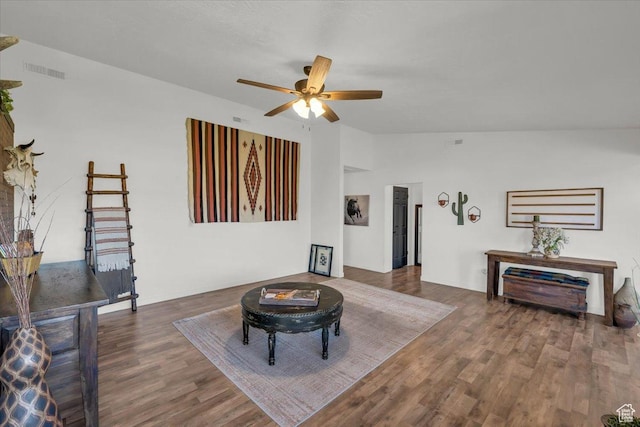 living room with a ceiling fan, vaulted ceiling, wood finished floors, and visible vents