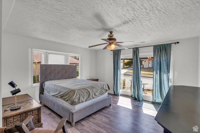 bedroom with a ceiling fan, access to exterior, wood finished floors, and a textured ceiling