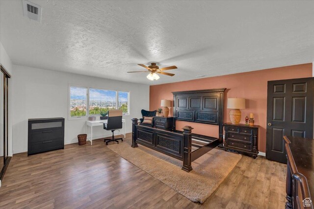 bedroom featuring visible vents, baseboards, light wood-style floors, and a textured ceiling