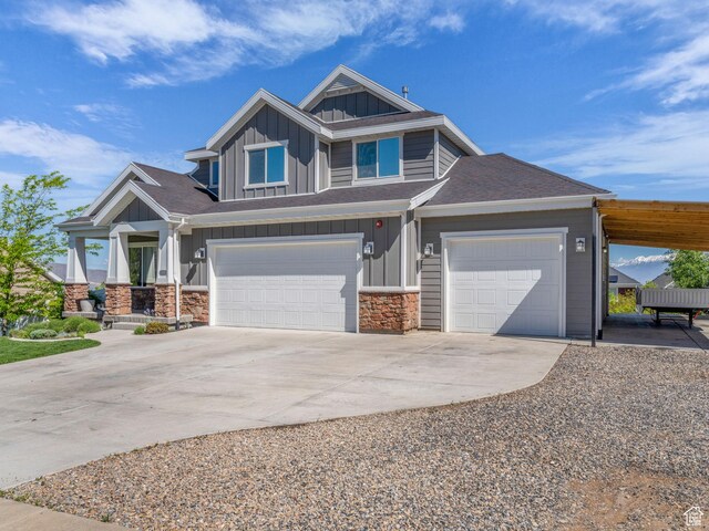 203 E Deer Run Loop Unit 40, Elk Ridge, UT 84651 - view of front of house with board and batten siding, concrete driveway, an attached garage, stone siding, and roof with shingles
