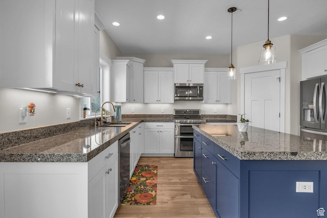 203 E Deer Run Loop Unit 40, Elk Ridge, UT 84651 - kitchen featuring appliances with stainless steel finishes, a sink, light wood-type flooring, blue cabinetry, and white cabinetry