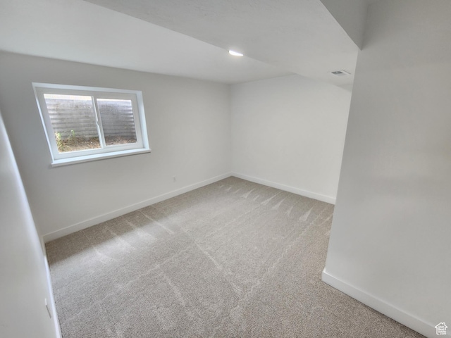 spare room featuring visible vents, baseboards, and light colored carpet
