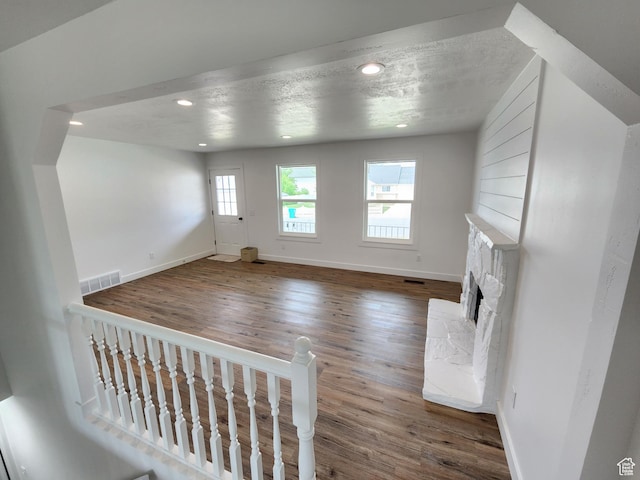 unfurnished living room with a fireplace with raised hearth, recessed lighting, baseboards, and wood finished floors
