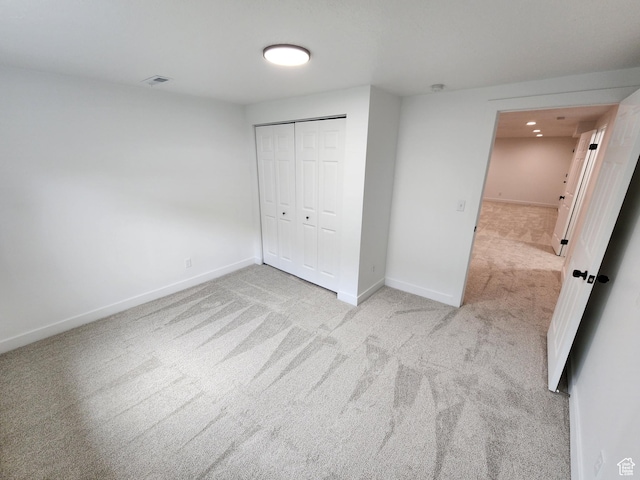 unfurnished bedroom featuring carpet, visible vents, a closet, and baseboards