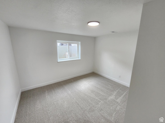 empty room featuring baseboards, carpet floors, and a textured ceiling