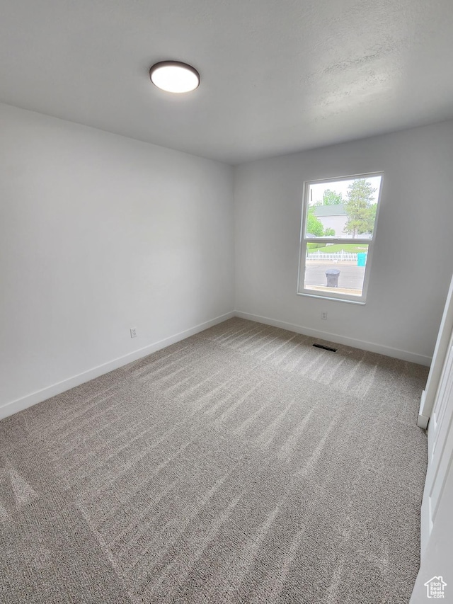 spare room featuring visible vents, baseboards, and carpet floors